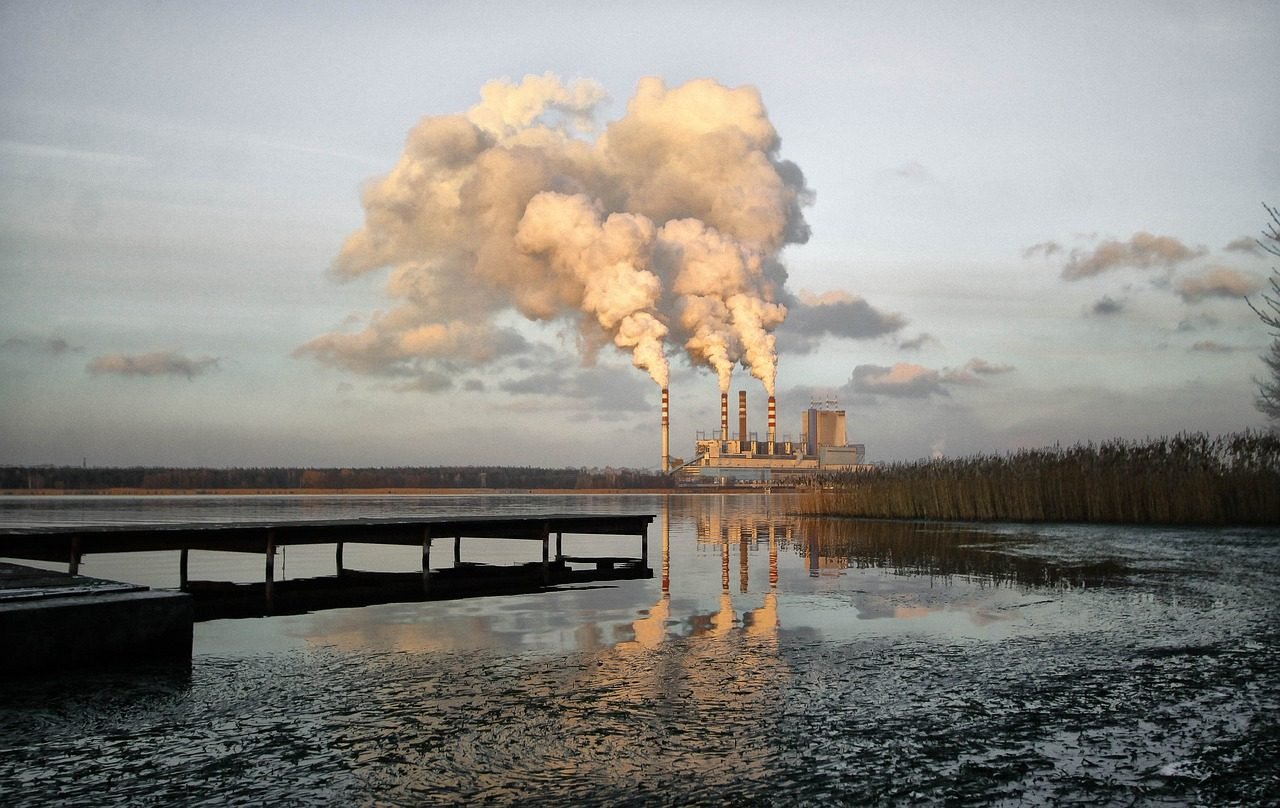 Industrial stacks emitting to atmosphere beside a lake
